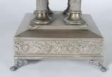 Fruteira com base de metal prateado decorado co... - Fruteira com base de metal prateado decorado com folhas de parreira e cachos de uvas em relevo, base quadrangular com quatro colunas sustentando...