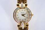 Bulova (1875),  - Relógio feminino de metal dourado e detalhes em  metal, mostrador branco com números e ponteiros dourados. Na caixa, funcionando.