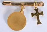 Alfinete de ouro 18 k., com pendentes represent... - Alfinete de ouro 18 k., com pendentes representando crucifixo com figura de Cristo e medalha sacra. (Por motivos de segurança a peça não se enco...