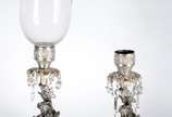Par de luminárias de metal prateado decorados c... - Par de luminárias de metal prateado decorados com figuras de flautistas sobre pedestal. Um deles com manga de cristal. Faltando alguns pingentes...