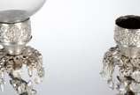 Par de luminárias de metal prateado decorados c... - Par de luminárias de metal prateado decorados com figuras de flautistas sobre pedestal. Um deles com manga de cristal. Faltando alguns pingentes...