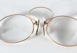 Três peças, sendo: dois pince nez e uma piteira... - Três peças, sendo: dois pince nez e uma piteira de âmbar com detalhes em ouro. No estojo. Um dos pince nez com arranhado e lascado.