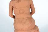 VALMIR NEVES,  - Escultura em barro cozido representando figura feminina sentada com flores no colo.