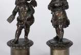 Par de antigas esculturas de petit bronze, repr... - Par de antigas esculturas de petit bronze, representando casal de crianças anjos, sobre pedestais com flores em relevo. Desgastes no metal.