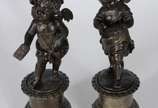 Par de antigas esculturas de petit bronze, repr... - Par de antigas esculturas de petit bronze, representando casal de crianças anjos, sobre pedestais com flores em relevo. Desgastes no metal.