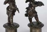 Par de antigas esculturas de petit bronze, repr... - Par de antigas esculturas de petit bronze, representando casal de crianças anjos, sobre pedestais com flores em relevo. Desgastes no metal.