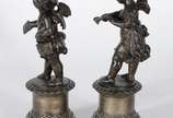 Par de antigas esculturas de petit bronze, repr... - Par de antigas esculturas de petit bronze, representando casal de crianças anjos, sobre pedestais com flores em relevo. Desgastes no metal.