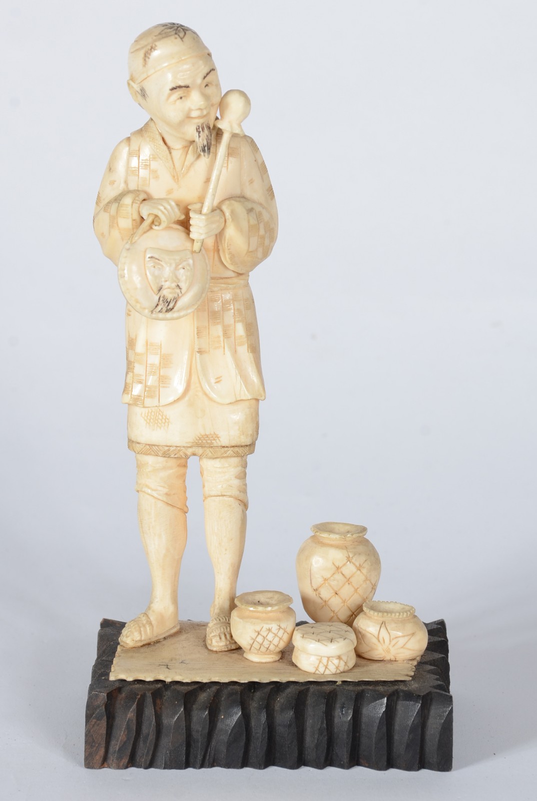 Estatueta de marfim representando figura masculina com potes, base de... - foto 1 de 5