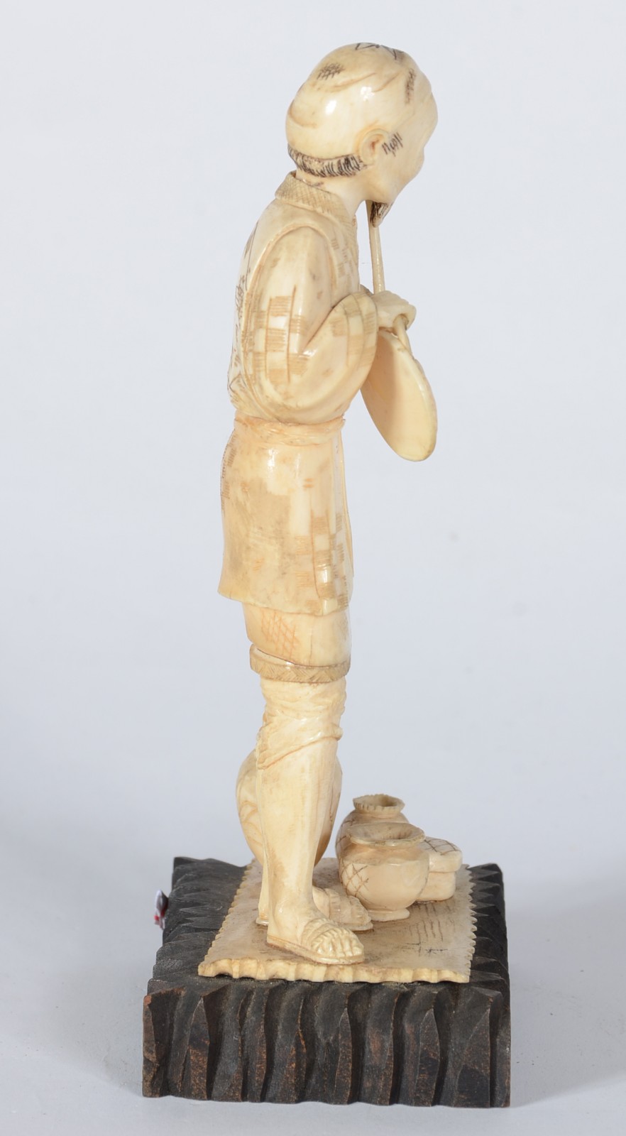 Estatueta de marfim representando figura masculina com potes, base de... - foto 2 de 5