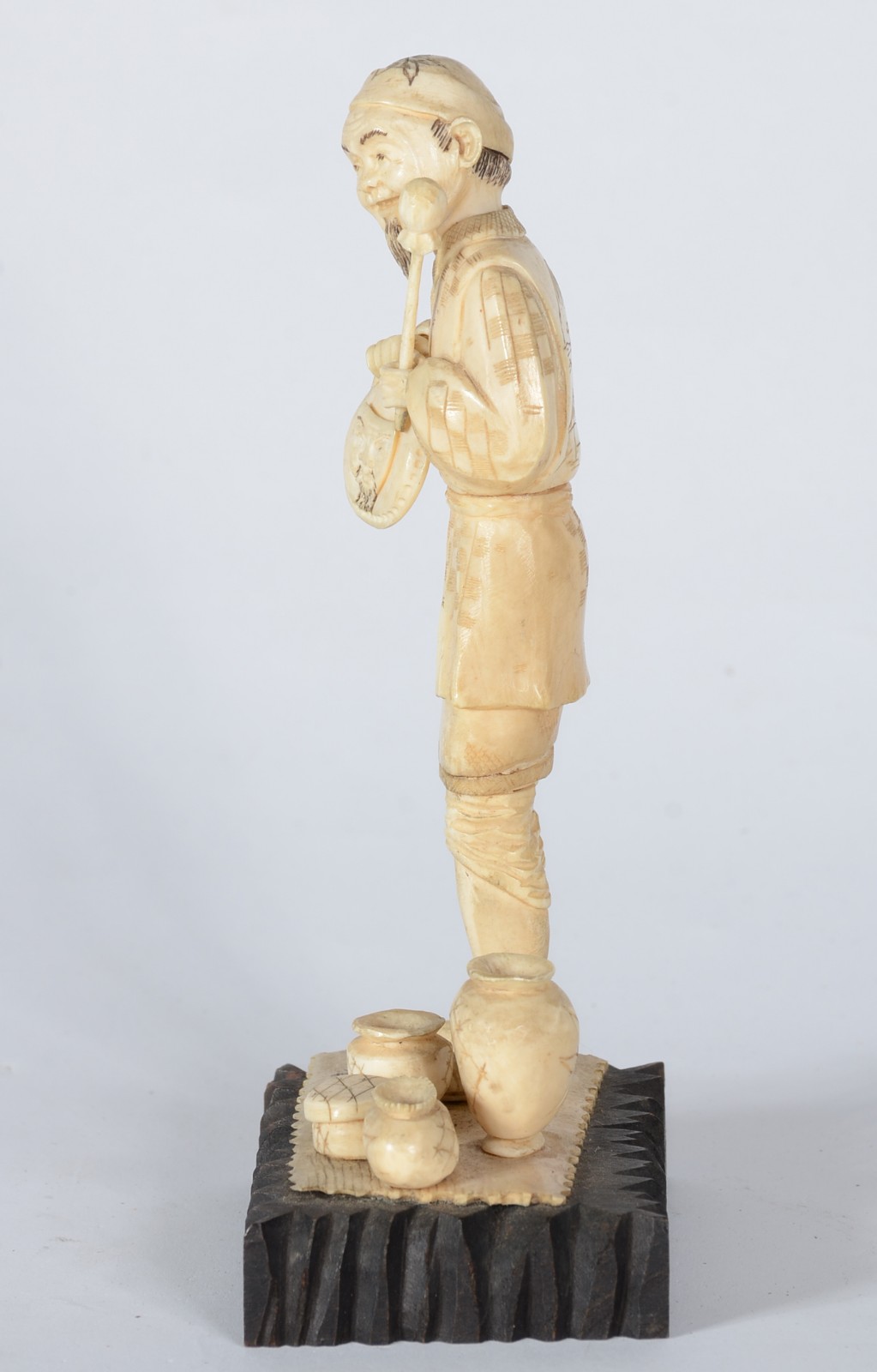 Estatueta de marfim representando figura masculina com potes, base de... - foto 3 de 5
