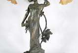 Lucien Alliot (1877-1967),  - Luminária de mesa para 2 luzes de bronze patinado representando Figura feminina e ramos de folhas. Assinado. Base de madeira. Mangas de vidro branco f