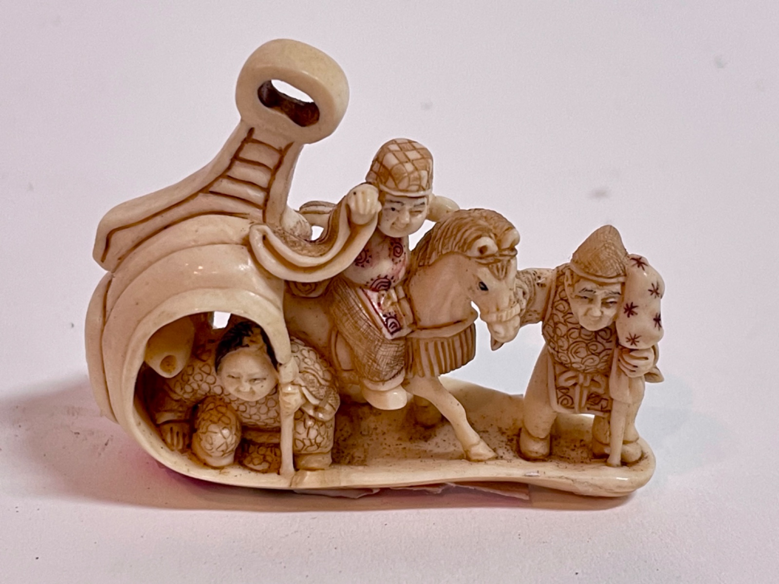 Netsuke de marfim representando figura a cavalo ladeado por figura... - foto 6 de 6