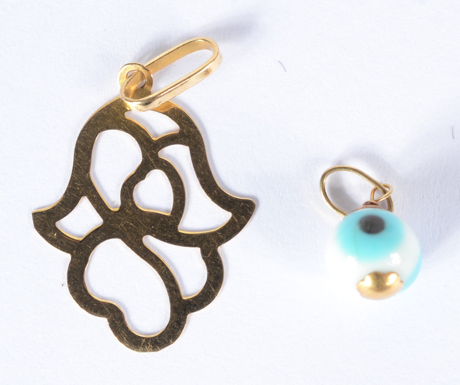 Dois pendentes de ouro 18 k., sendo uma mão de Hamsa com vazados e... - foto 1 de 2