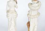 Par de estatuetas de porcelana portuguesa Época... - Par de estatuetas de porcelana portuguesa Época" nas cores branca e dourado, representando damas de época com chapéus, leque e sombrinha. Douraç...