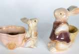 Duas esculturas de porcelana policromada repres... - Duas esculturas de porcelana policromada representando coelhos com cestos.