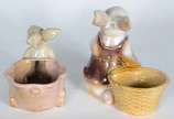 Duas esculturas de porcelana policromada repres... - Duas esculturas de porcelana policromada representando coelhos com cestos.