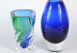 Dois vasos de vidro decorativo, sendo um azul e... - Dois vasos de vidro decorativo, sendo um azul e verde e outro azul com pequenas bolhas internas (batida na base).