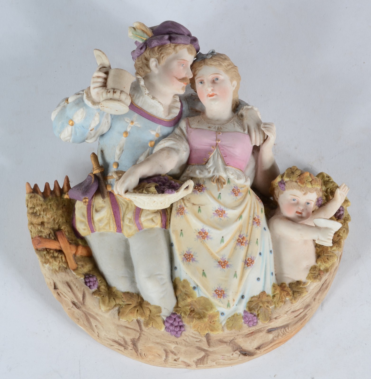 Placa de biscuit policromado representando casal com cachos de uvas e... - foto 1 de 2