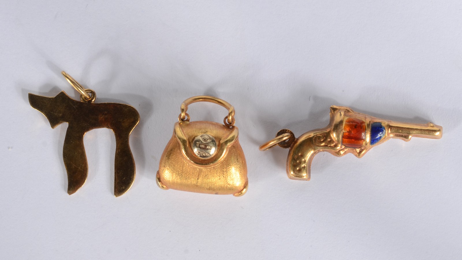 Três pendentes de ouro 18k., sendo uma bolsa, cachorro estilizado e... - foto 1 de 3
