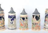 Conjunto com 4 tankards de cerâmica alemã decor... - Conjunto com 4 tankards de cerâmica alemã decoradas com figuras típicas em relevo policromado, tampas em pewter; e, uma caneca para cerveja de p...