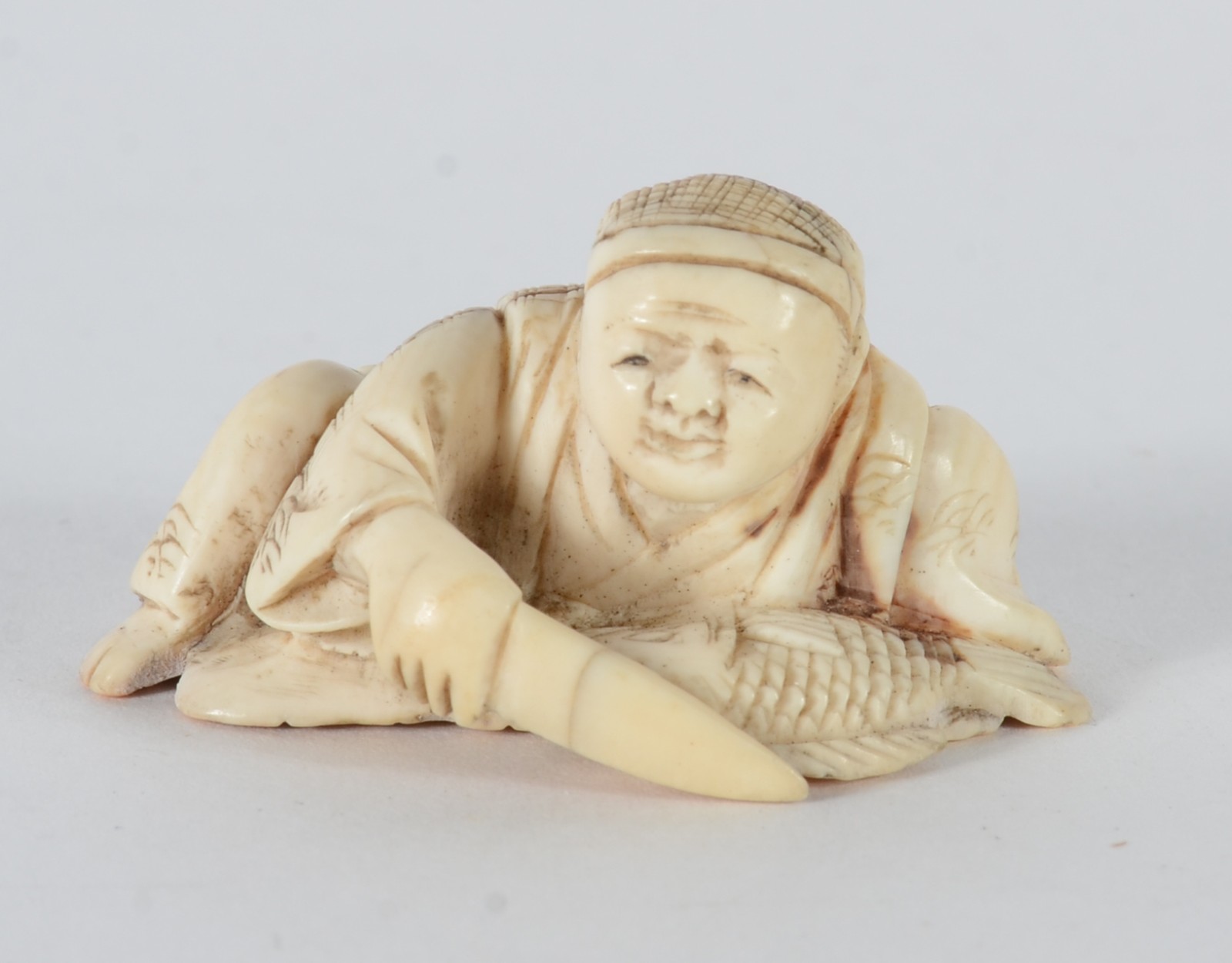 Netsuke de marfim representando figura masculina com faca e peixe... - foto 1 de 5