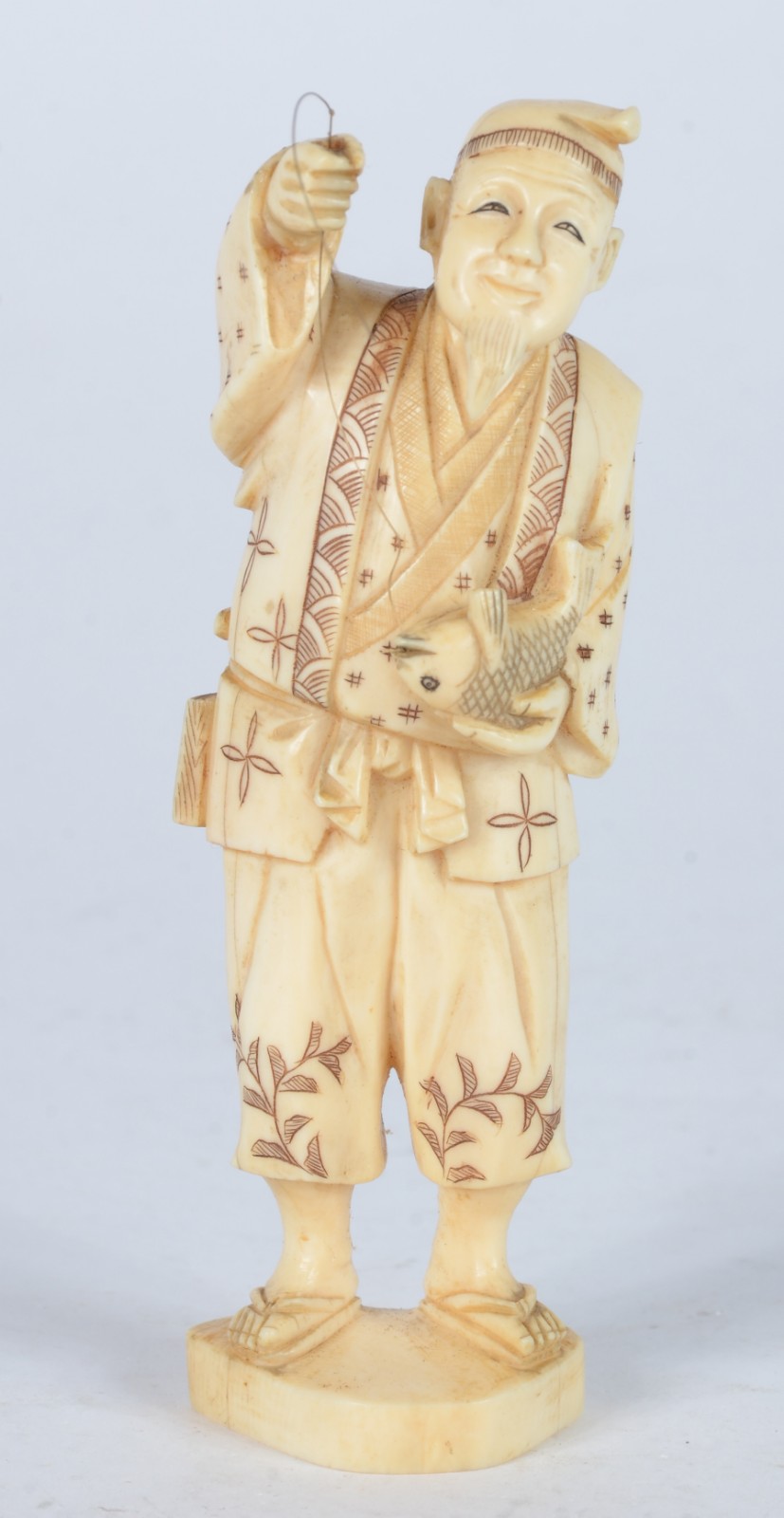 Escultura de marfim representando figura masculina com anzol e peixe. - foto 1 de 5