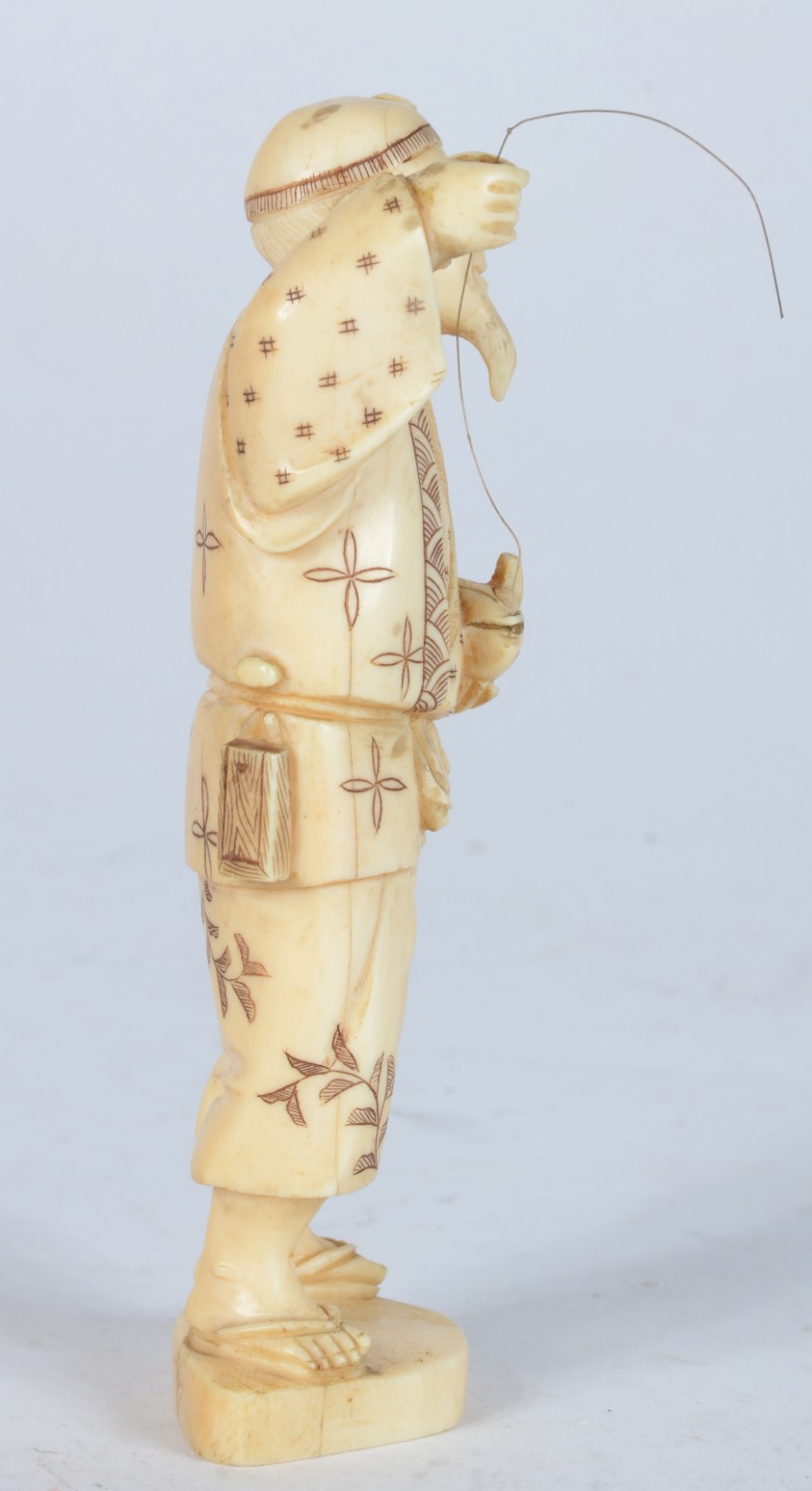 Escultura de marfim representando figura masculina com anzol e peixe. - foto 2 de 5