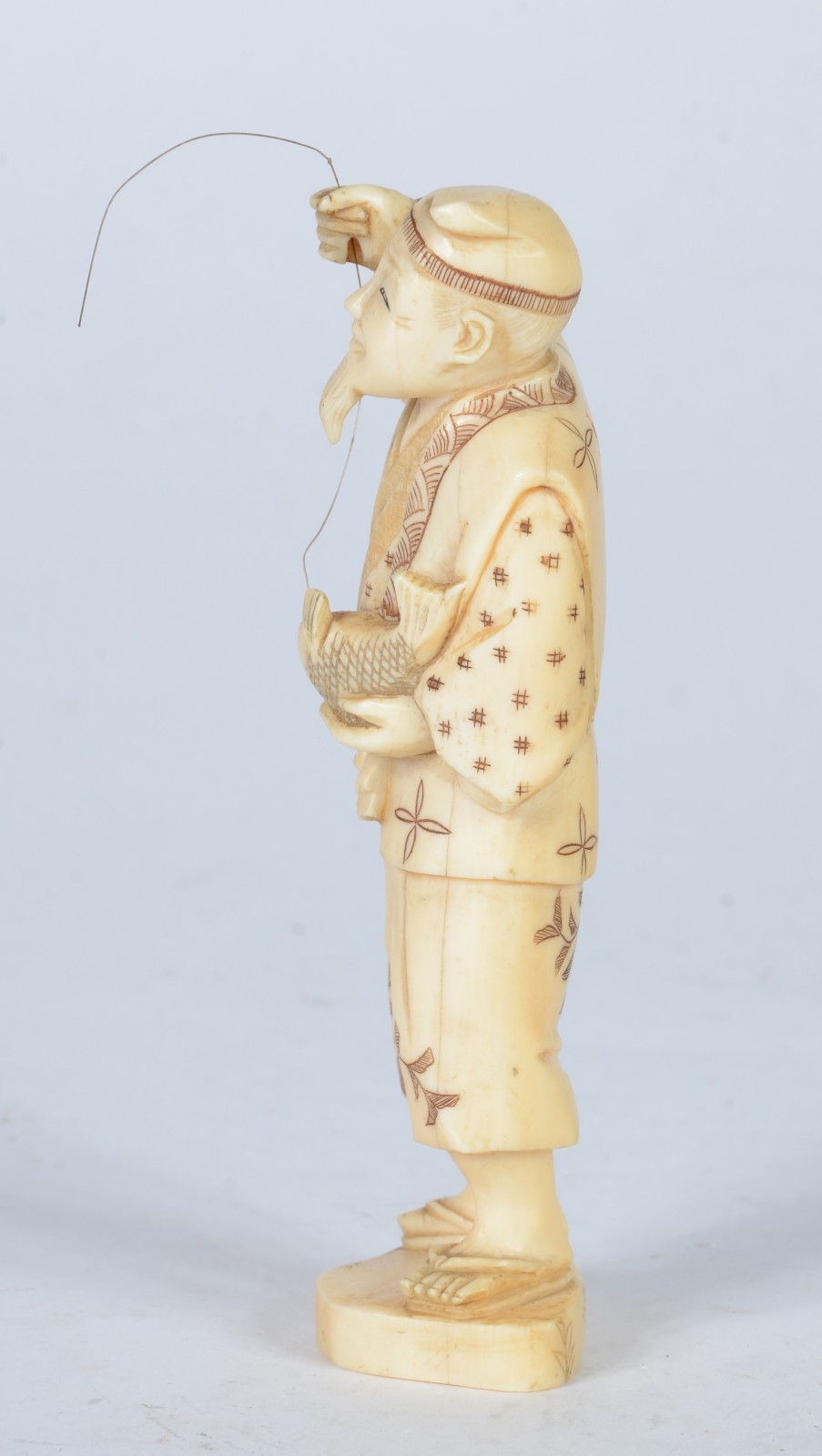 Escultura de marfim representando figura masculina com anzol e peixe. - foto 3 de 5
