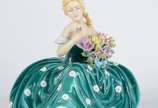 Estatueta de porcelana policromada representand... - Estatueta de porcelana policromada representando jovem com flores. Pétalas com lascados.