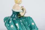 Estatueta de porcelana policromada representand... - Estatueta de porcelana policromada representando jovem com flores. Pétalas com lascados.