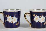 Par de xícaras de porcelana na cor azul cobalto... - Par de xícaras de porcelana na cor azul cobalto com flores em policromia.