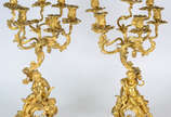 Par  de imponentes candelabros de bronze dourad... - Par  de imponentes candelabros de bronze dourado a ouro , para 6 velas cada ,  bases com figuras de cupidos segurando ramos de flores .