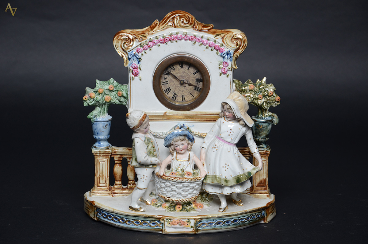 Relógio alemão com figuras de crianças em porcelana policromada...