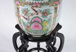 Cachepot de porcelana oriental decorado com flo... - Cachepot de porcelana oriental decorado com flores e figuras típicas em policromia, base de madeira. Apresenta restauro.