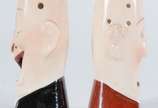 Par de paliteiros de porcelana policromada na f... - Par de paliteiros de porcelana policromada na forma de rostos masculinos.