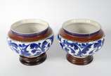 Par de cachepots de cerâmica decoração floral e... - Par de cachepots de cerâmica decoração floral em tons de azul, bases de madeira (um deles com fio de cabelo)