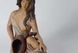 Escultura de cerâmica policromada representando... - Escultura de cerâmica policromada representando figura feminina com concha, perna colada.