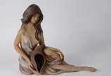 Escultura de cerâmica policromada representando... - Escultura de cerâmica policromada representando figura feminina com concha, perna colada.