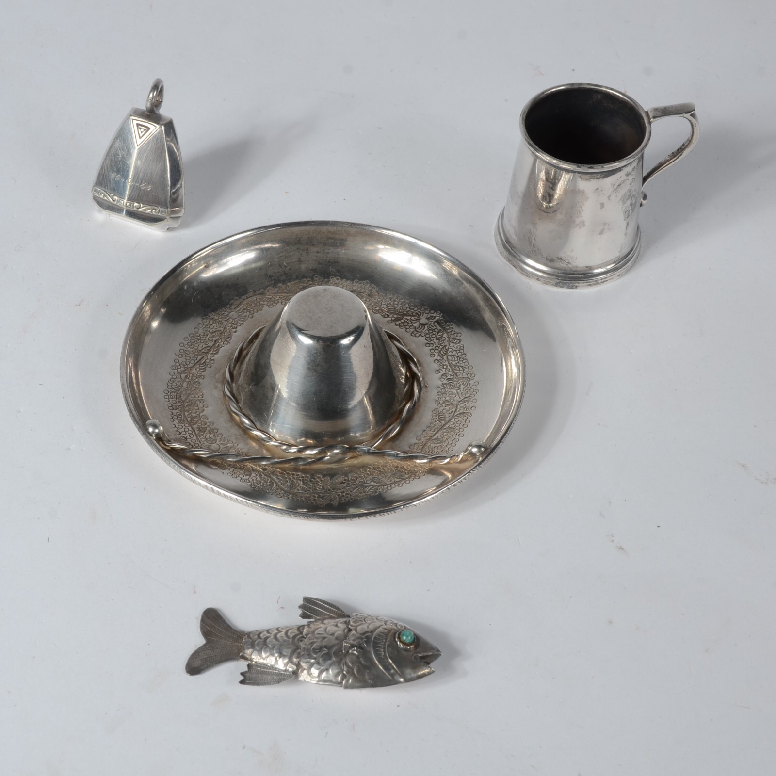 Quatro pequenas peças de prata, sendo: chapéu mexicano, caneca, peixe... - foto 1 de 7