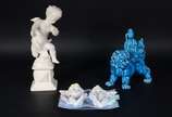 Três esculturas de porcelana, sendo : Anjo sobr... - Três esculturas de porcelana, sendo : Anjo sobre pedestal (dedos com defeito); Cão de Fó na cor azul (restauro); placa com rostos de anjos em po...