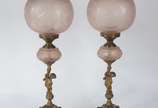 Par de luminárias de metal dourado decoradas co... - Par de luminárias de metal dourado decoradas com figuras de "Pucci"nas bases, globos de vidro fosco rosado.