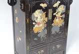 Movel chines de lacca negra decorada com figura... - Movel chines de lacca negra decorada com figuras de crianças e peixes em policromia, 2 portas com prateleira interna e duas gavetinhas na parte ...