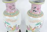 Par de vasos de porcelana chinesa decorados com... - Par de vasos de porcelana chinesa decorados com figuras típicas em policromia e guirlandas florais, acompanham peanhas de madeira.