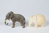 Duas pequenas esculturas representando elefante... - Duas pequenas esculturas representando elefantes, sendo uma de marfim e outra de bronze com presas de marfim.