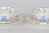 Par de xícaras de chá de porcelana austríaca, m... - Par de xícaras de chá de porcelana austríaca, monogramas em azul, decoração floral em policromia e realces dourados.
