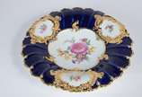 Meissen (1708),  - Elegante prato de porcelana alemã de Meissen decorado com flores em policromia com realces dourados sobre fundo azul cobalto, borda em gomos.