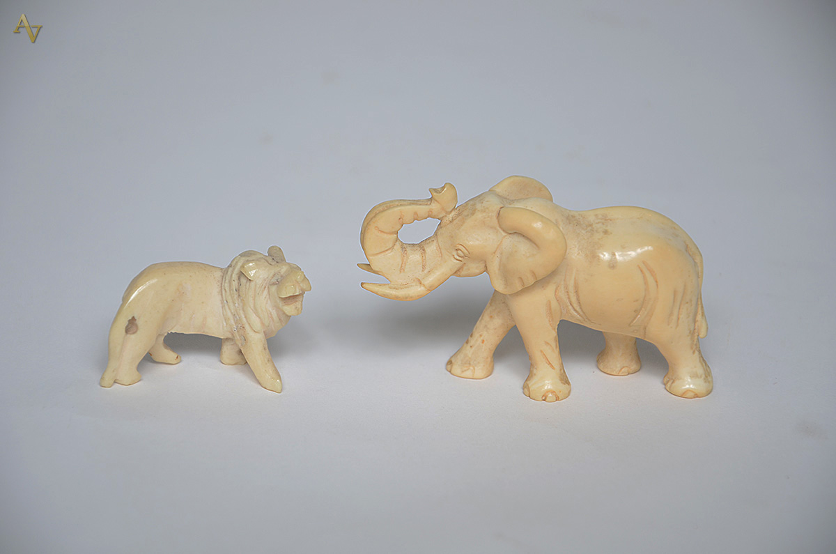 Duas peças de marfim, sendo elefante e leão. Alturas de 3 cm e 4 cm. - foto 1 de 2