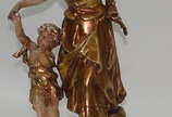 Auguste Moreau (1834-1917),  - Escultura de petit bronze patinada de dourado representando Mulher com criança, assinada . Pátina descascando em pequenas partes.