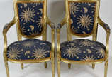 Par de poltronas de madeira patinadas em dourad... - Par de poltronas de madeira patinadas em dourado, estofamento forrado com tecido azul estampado.