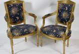Par de poltronas de madeira patinadas em dourad... - Par de poltronas de madeira patinadas em dourado, estofamento forrado com tecido azul estampado.